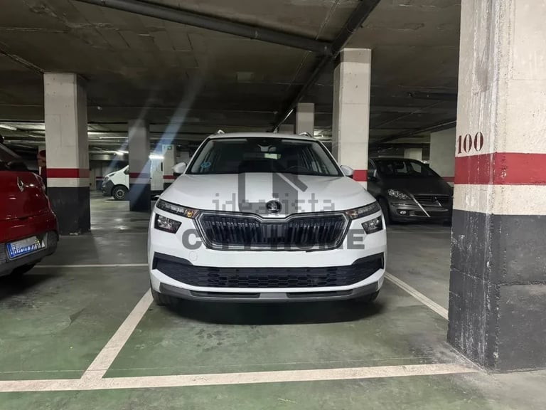 White Skoda SUV parked in underground garage with concrete pillars and red-marked parking space