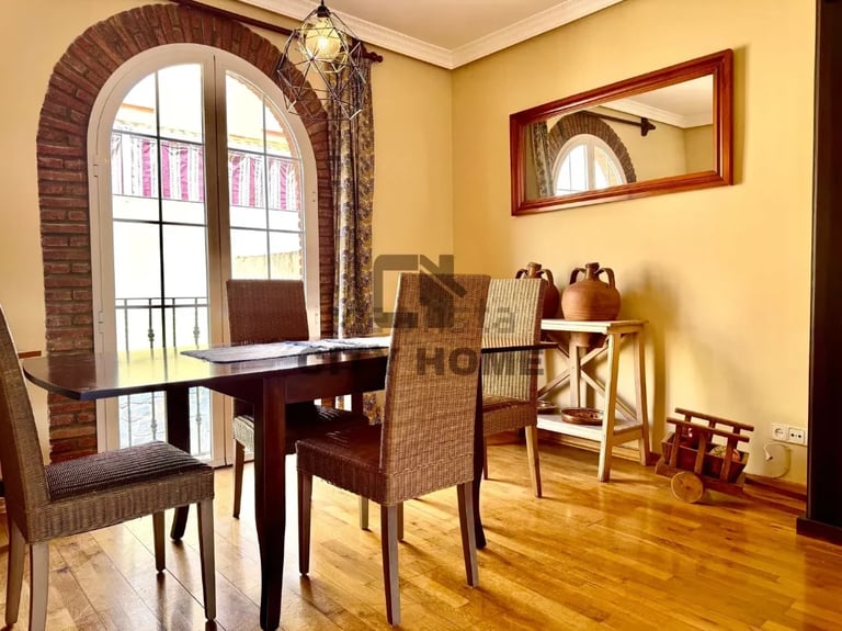 Bright dining room with arched brick doorway, wooden furniture, yellow walls, and hardwood floors