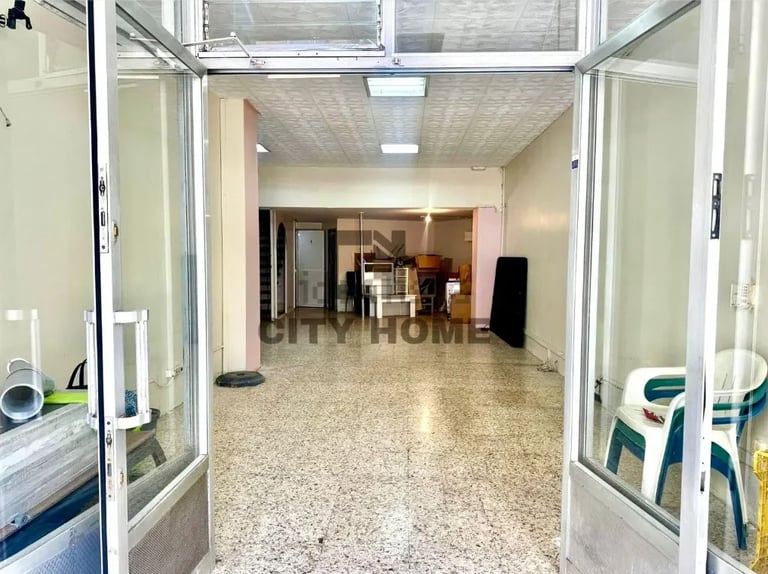 Empty retail or office space with polished concrete floor, glass doors, white walls, and fluorescent lighting