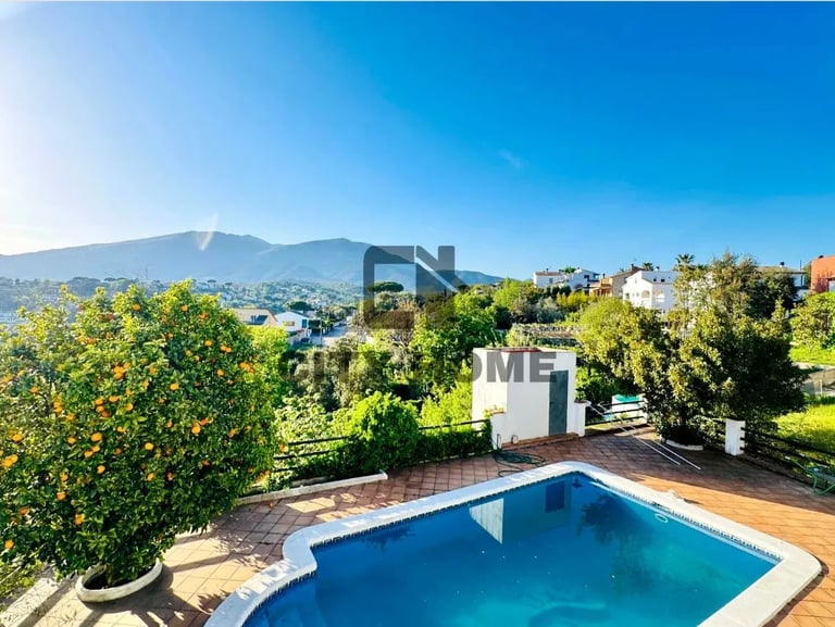 Modern home with blue swimming pool overlooking mountains and green landscape under clear blue sky